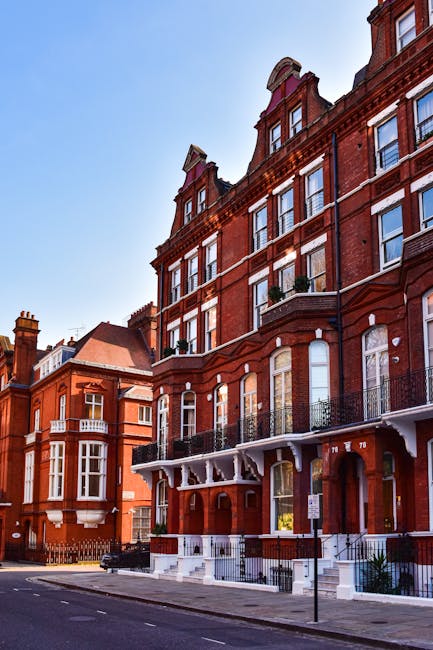 A multi-storey red-brick residential building with ornate white stone balconies and decorative columns at the entrance, located at 13-36 Campden Hill Court in South Kensington. The building has severa