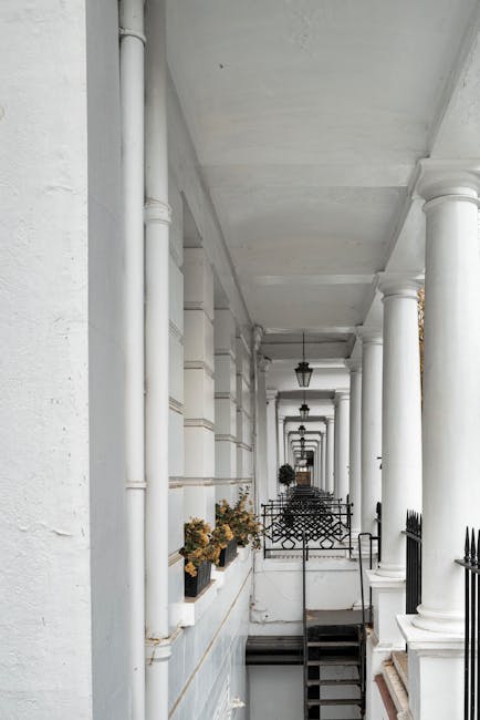 A narrow cobblestone residential street in South Kensington lined with terraced houses featuring white facades, some with small balconies and potted plants outside. The street is gently curved and fla